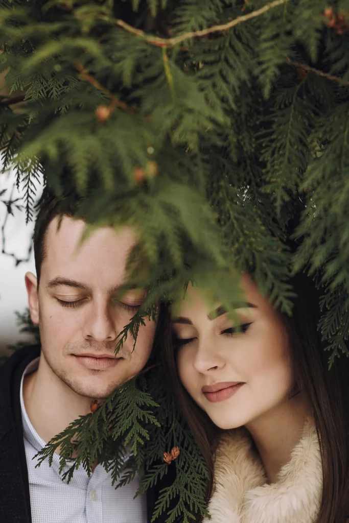 gorgeous-wedding-couple-embracing-winter-snowy-park-stylish-bride-coat-groom-gently-hugging-green-trees-winter-forest-romantic-sensual-moment-newlyweds