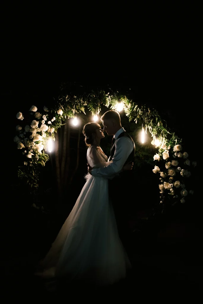 wedding-day-bride-groom-night-vows-near-arch-with-lights-background-fireworks